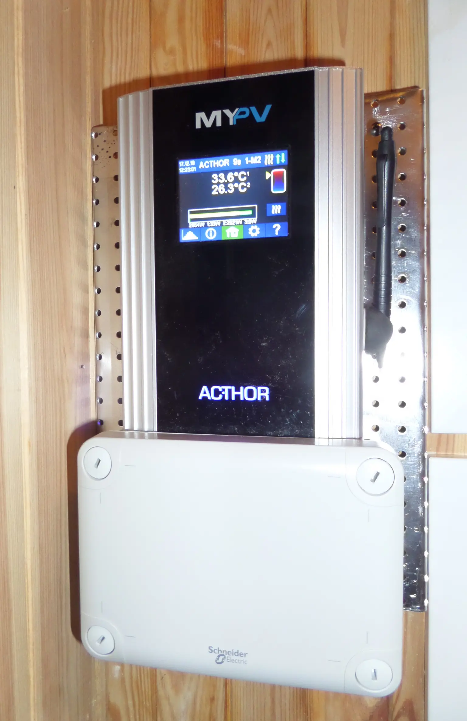 my-PV AC•THOR solar power controller mounted on a wooden wall, with digital display showing temperature readings.