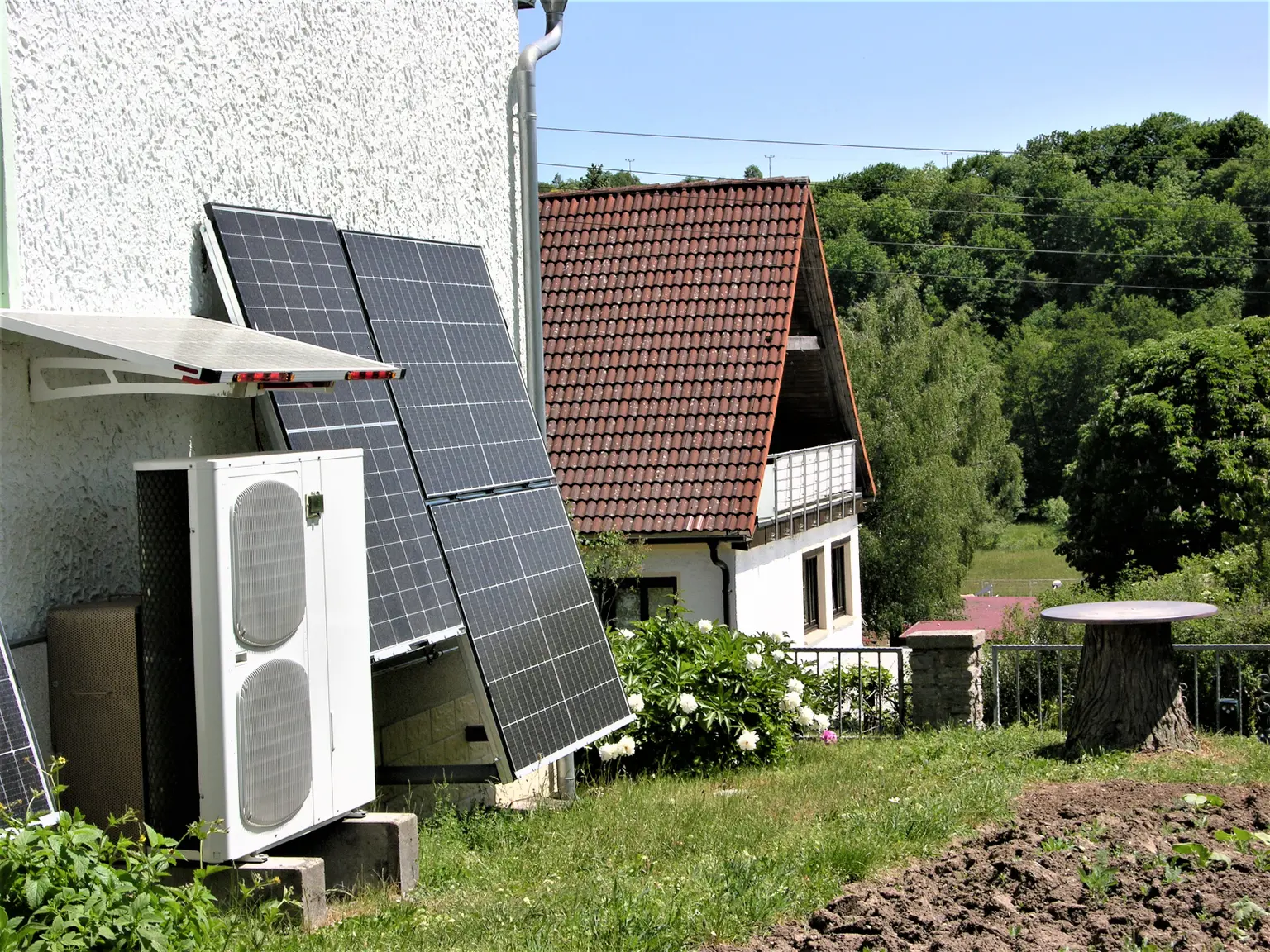 ChatGPT:  House with white facade, brown-framed windows, and PV panels on the facade and neighboring houses in background.