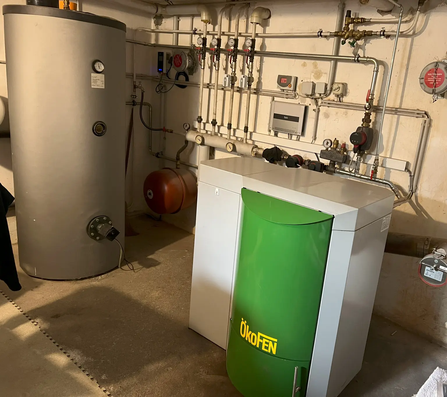 ChatGPT: In the boiler room, a gray water heater with my-PV heating rods and an Ökofen heating system can be seen.