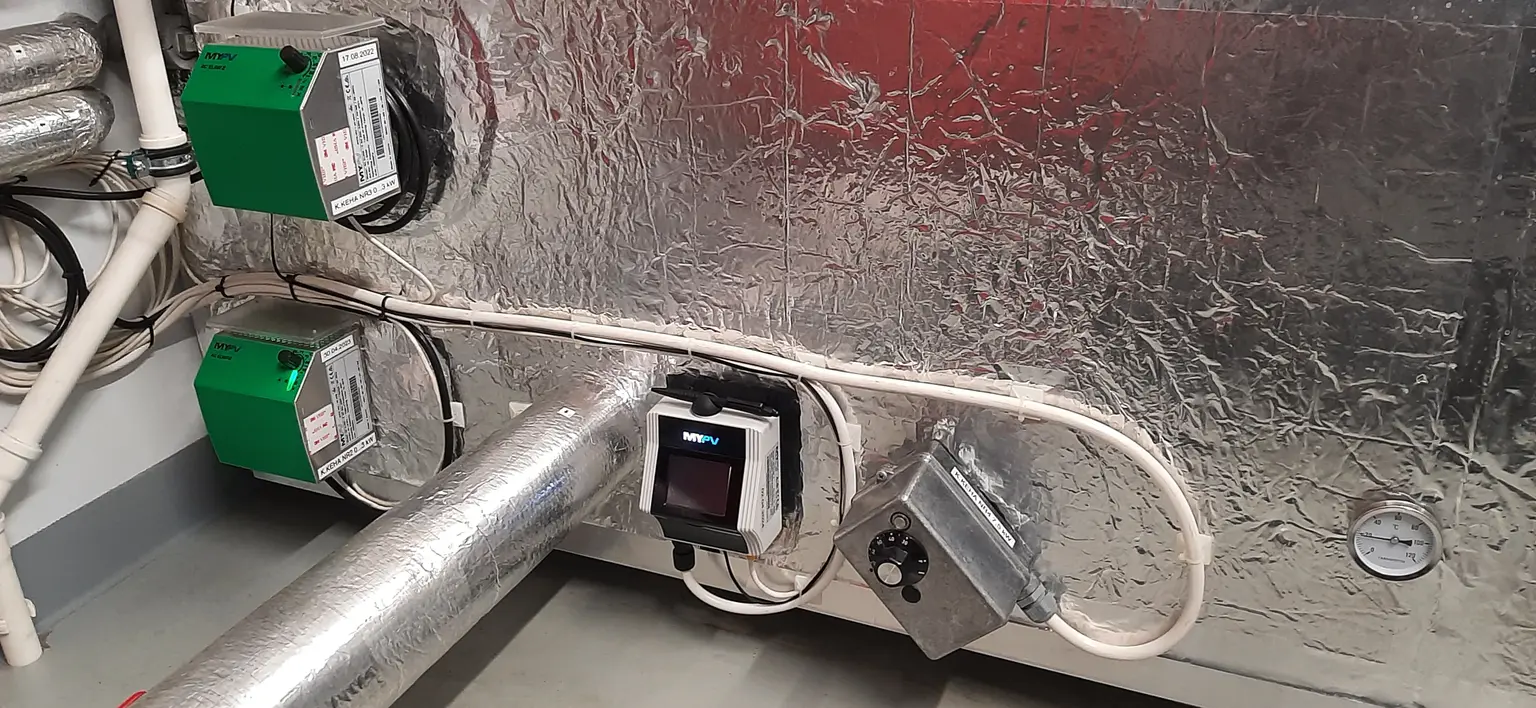 Two AC ELWA-E units and one AC ELWA 2 are connected to the thermal storage, with multiple pipes extending from it.