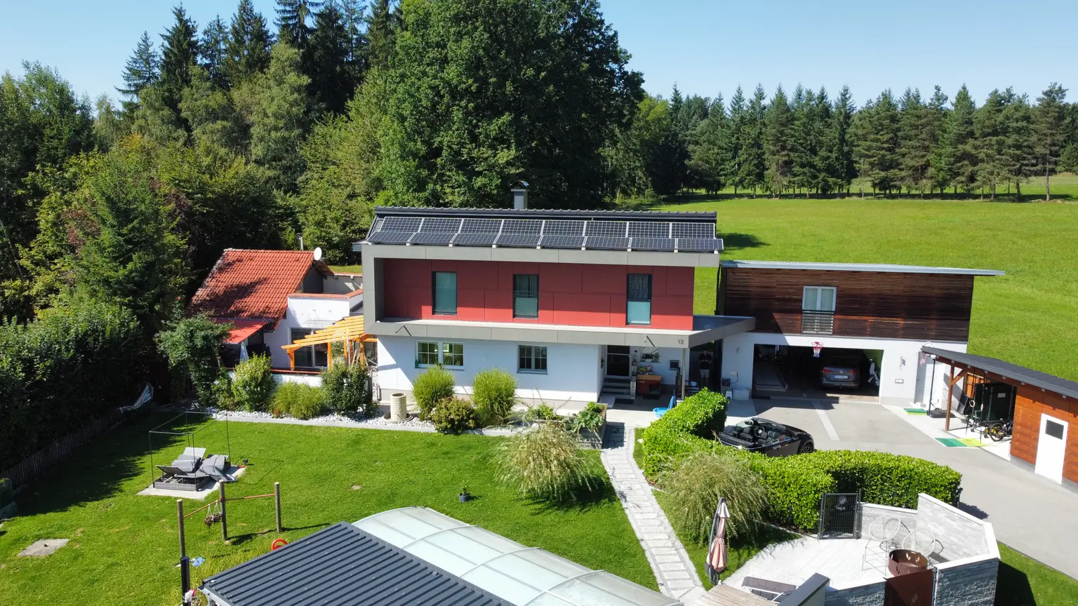 Solar panels on the roof of a modern architect’s house with large garden, fire pit, and relaxation area.