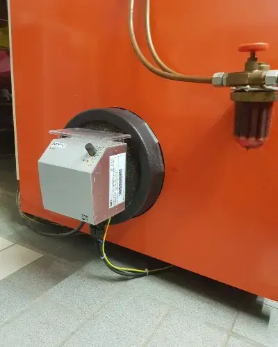 A gray control box attached to an orange industrial machine with visible wires and a valve on the right.