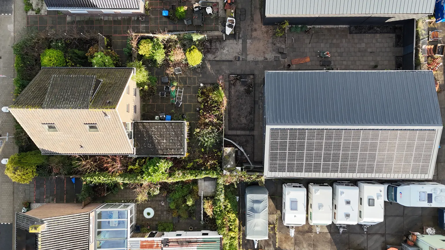Top view of houses and campervans with photovoltaic panels installed on several rooftops in the neighborhood.