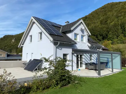 Light blue single-family house with PV panels on the roof.