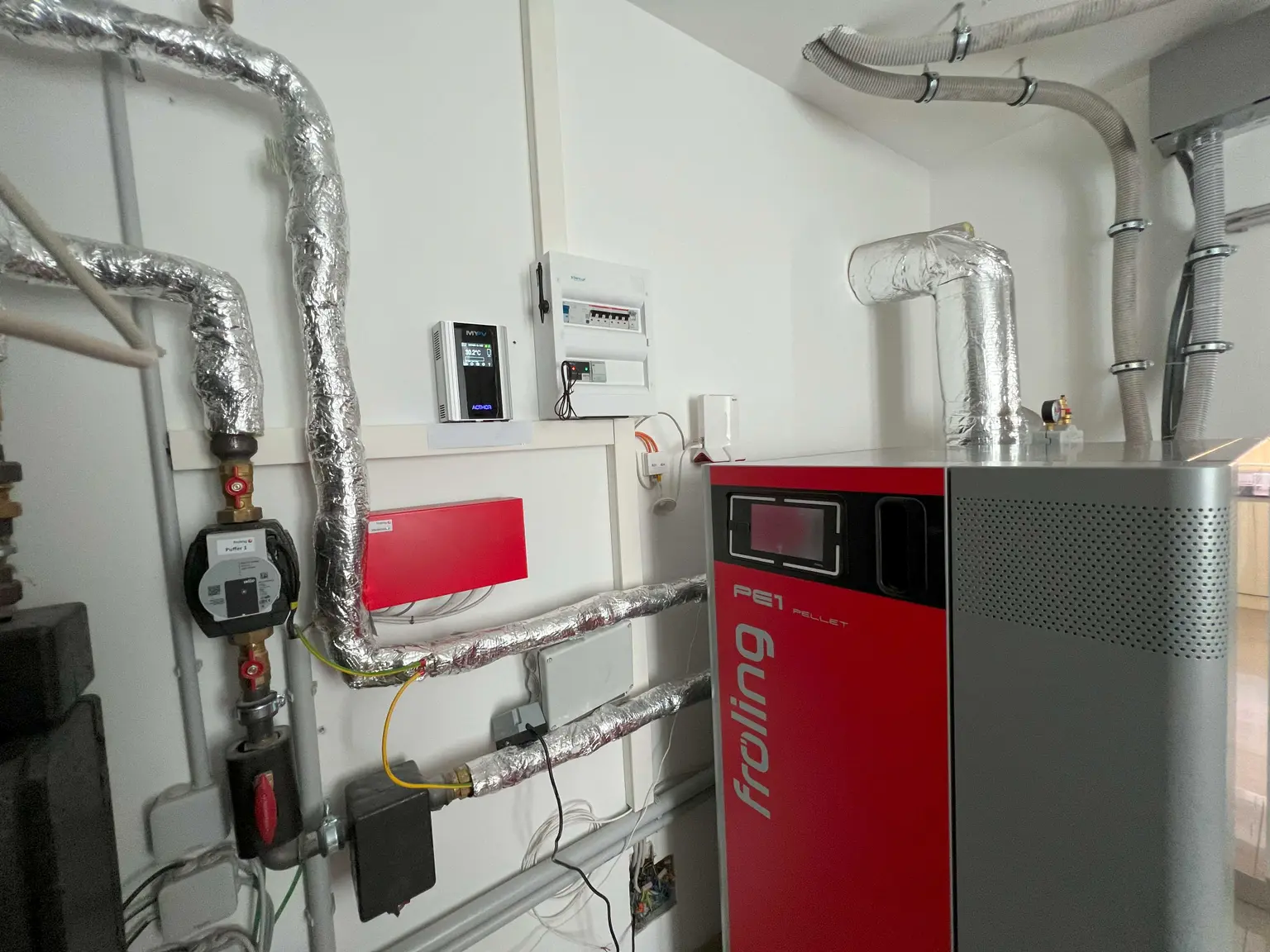 ChatGPT:  Pellet heating system in boiler room with wall-mounted AC•THOR 9s and fuse box.
