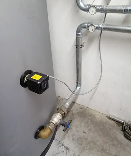 Pipes with gauges and valves connected to a large tank with my-PV screw-in heater in a utility room.