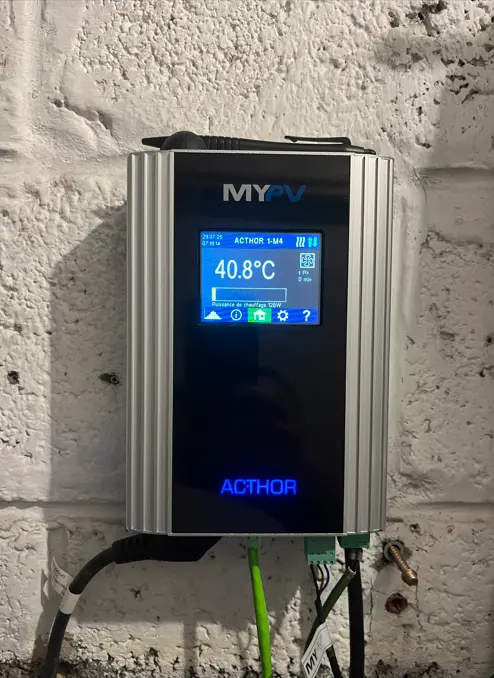 A digital device labeled "MYPV" displays a temperature of 40.8°C, mounted on a textured white wall with connected cables.
