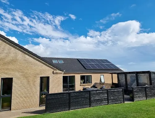 Brick house with solar panels on the roof and a fenced terrace