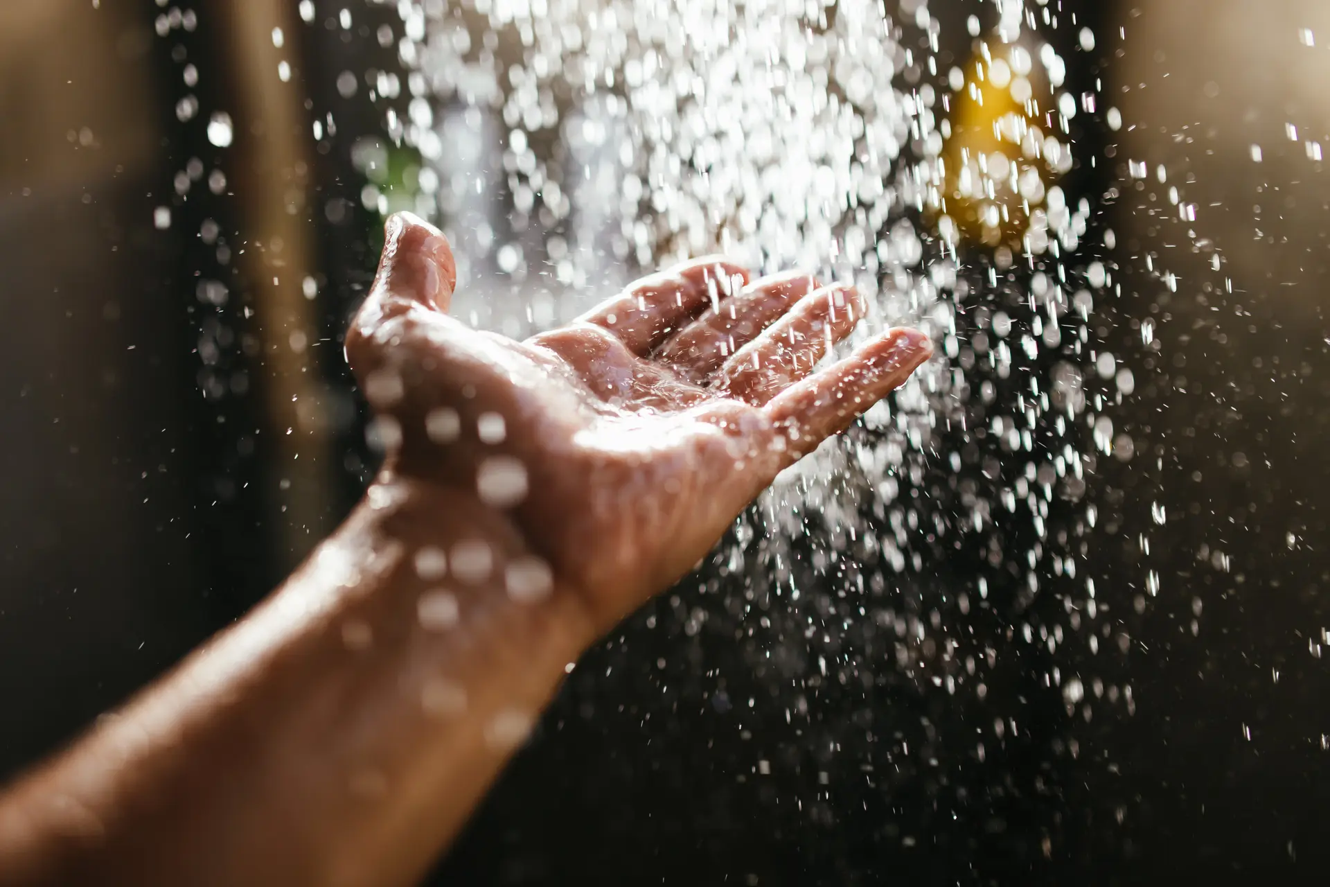 A hand reaching into falling water symbolizes the comfort and warmth of solar-heated water in this promotional image.