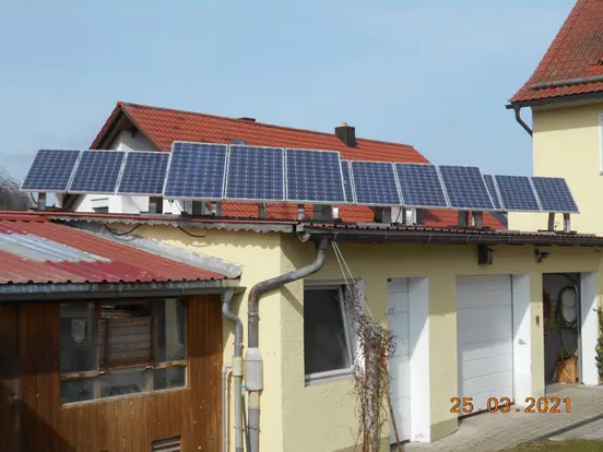 Solar panels on the roof of a yellow building with garage under a clear blue sky.
