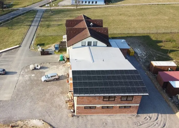 Bird’s-eye view of an industrial building with a new, unfinished extension and two cars in the driveway