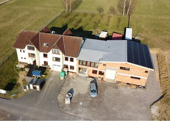 Bird’s-eye view of an industrial building with a new, unfinished extension and two cars in the driveway