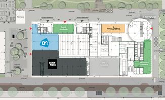 Architectural site plan showing a building layout with marked areas, entrances, and surrounding greenery. Various sections are labeled in color.