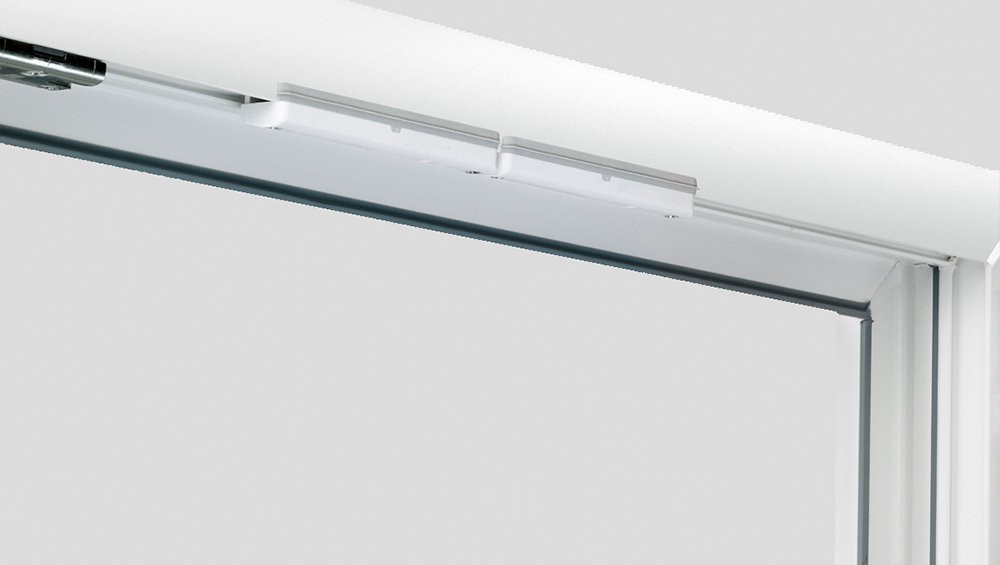 A close-up view of a white sliding glass door with a white ceiling and a white wall.