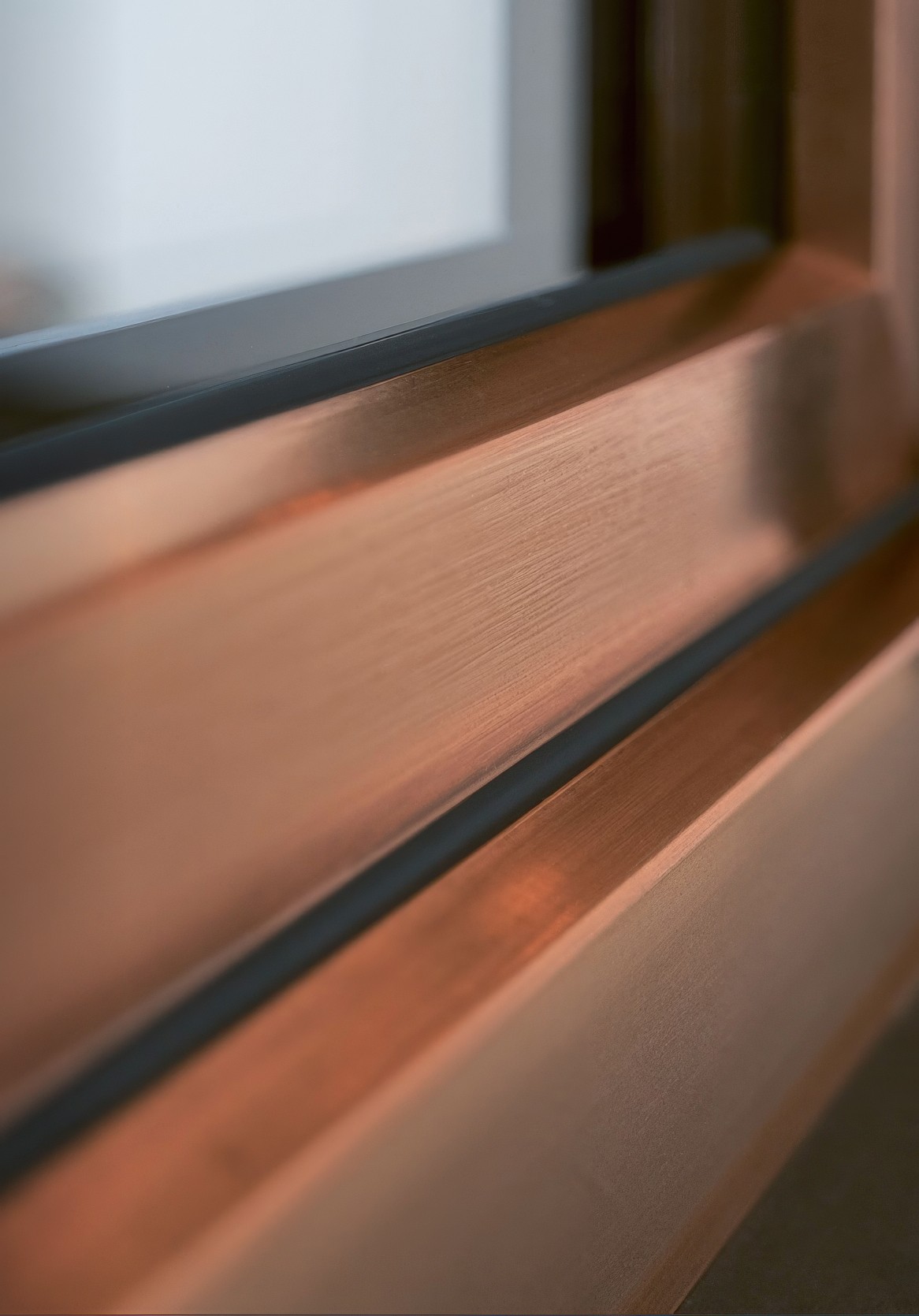 Vista de cerca de un marco de ventana de color cobre con un borde negro y un cristal blanco.