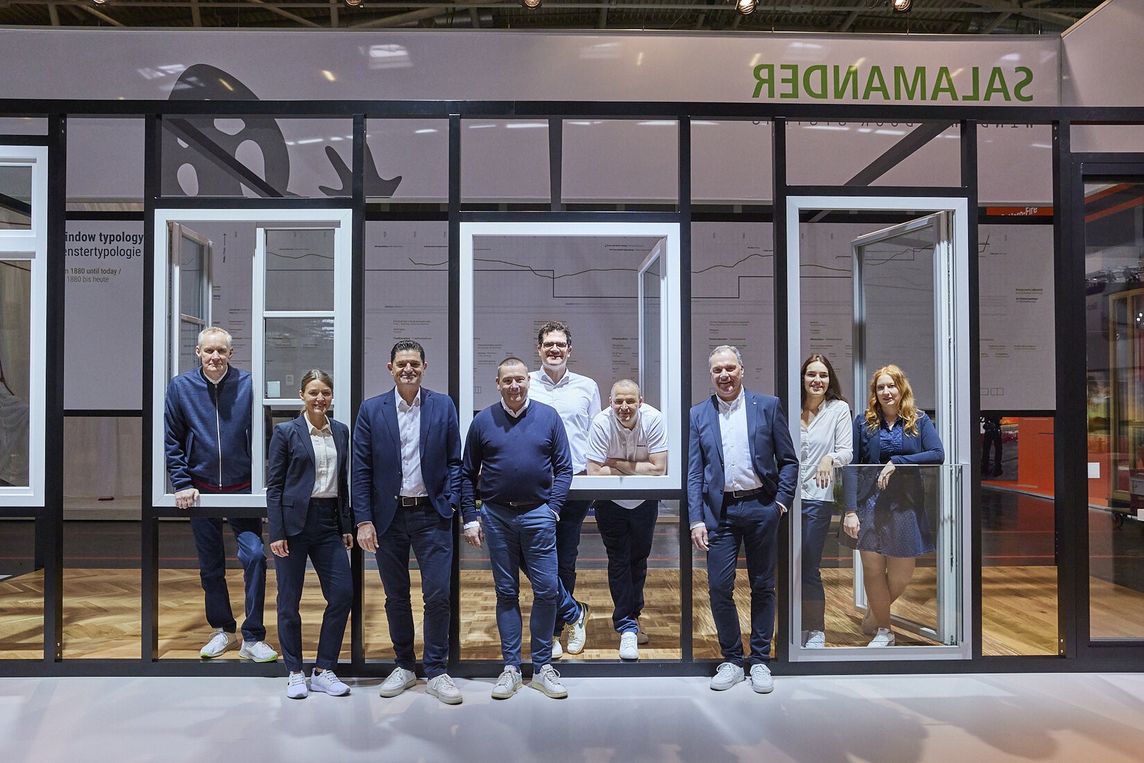A group of people standing in front of a glass wall with the text "SAINT-GOBAIN" on top.