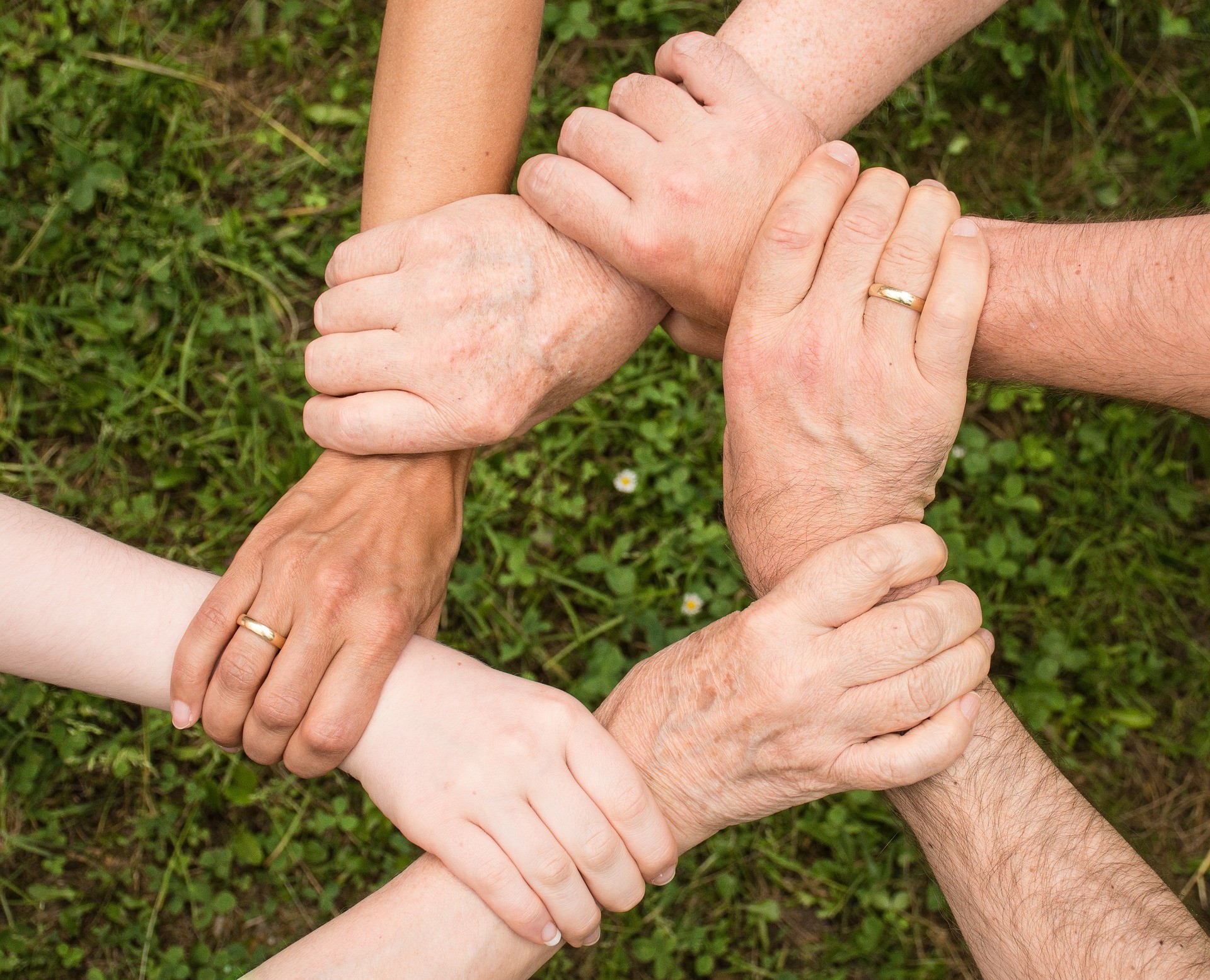 A group of people with their hands together in a circle, symbolizing unity and teamwork.
