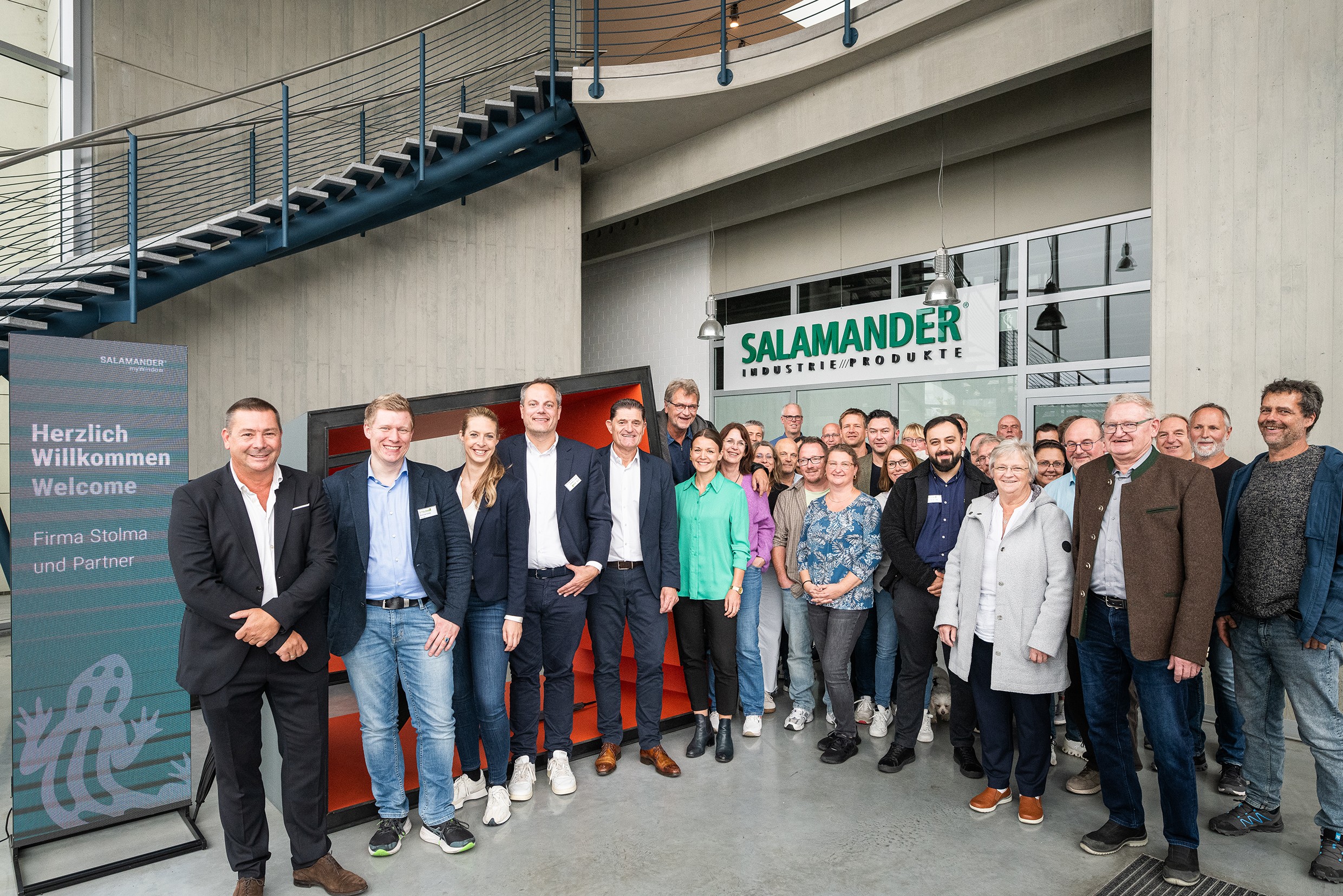 Um grupo de pessoas em pé em frente a um edifício com uma placa que diz Salamandra.