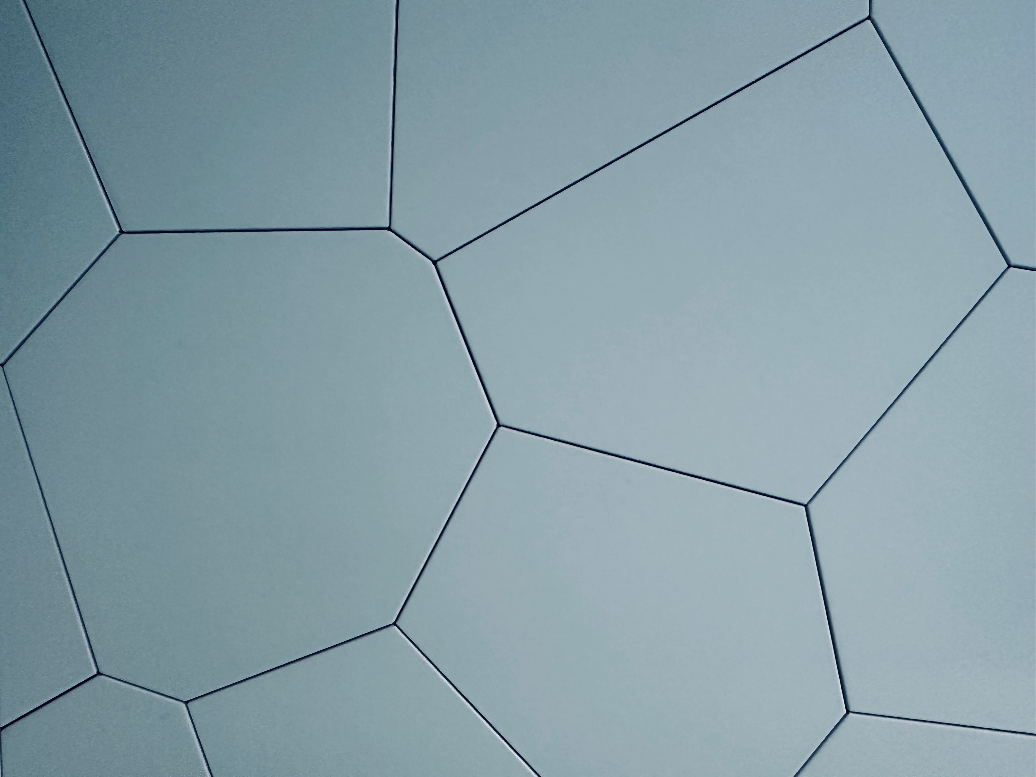 Close-up of a blue geometric pattern with hexagonal shapes and black lines, resembling a modern architectural design.