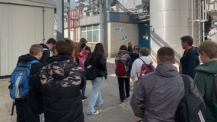 Um grupo de estudantes com mochilas está parado do lado de fora de um edifício.