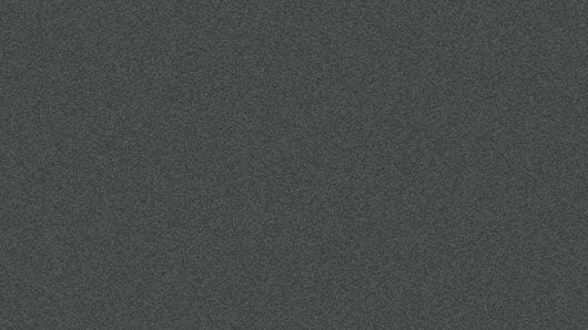 Eine Nahaufnahme einer strukturierten, grauen Oberfläche mit einem leicht rauen und unebenem Aussehen, möglicherweise aus einem Material wie Beton oder Stein.