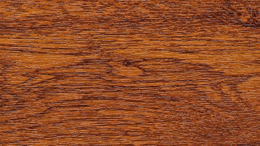 Eine Nahaufnahme einer Holzoberfläche mit einer satten, warmen braunen Farbe und sichtbaren Maserungsmustern.