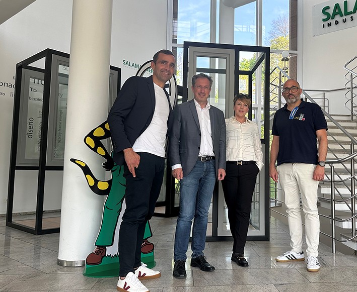 Four people standing in front of a building with a sign that says "Salam Industries".