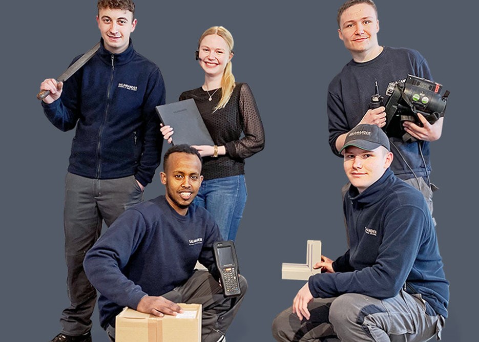 Four people in uniforms posing for a photo. One is holding a sword, another is holding a book, another is holding a camera, and the last one is holding a box.