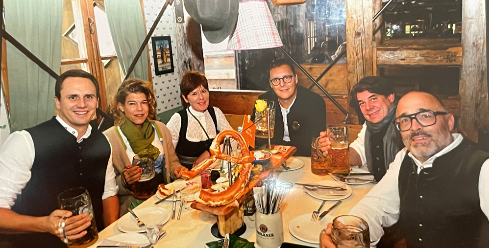 A group of people are sitting at a table in a restaurant, smiling and posing for a photo.