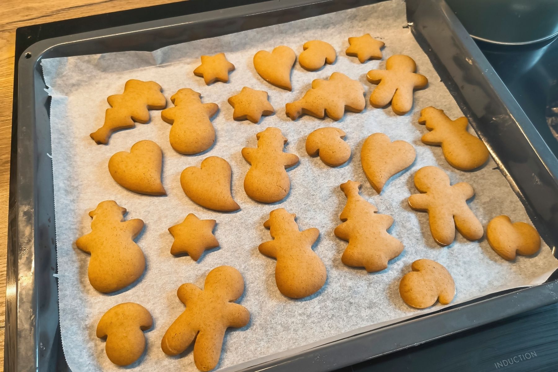 Plech s čerstvě upečenými perníčky ve tvarech hvězd, stromečků, srdíček a postaviček na pečicím papíru. Recept připravily Ségry v kuchyni.