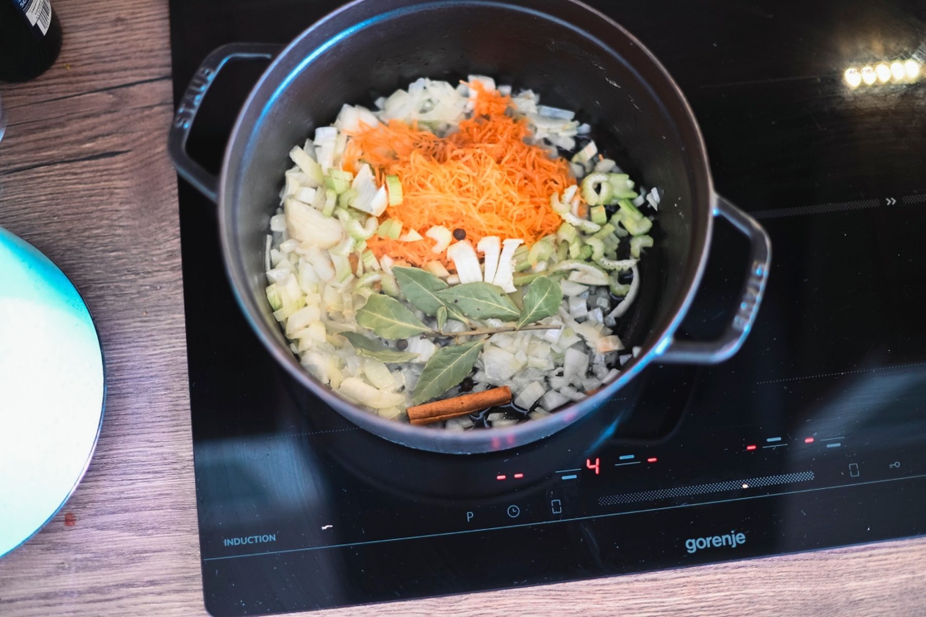 Nakrájená cibule, řapíkatý celer, nastrouhaná mrkev, bobkové listy a skořice v hrnci na sporáku. Recept připravil Vojta Poštulka.
