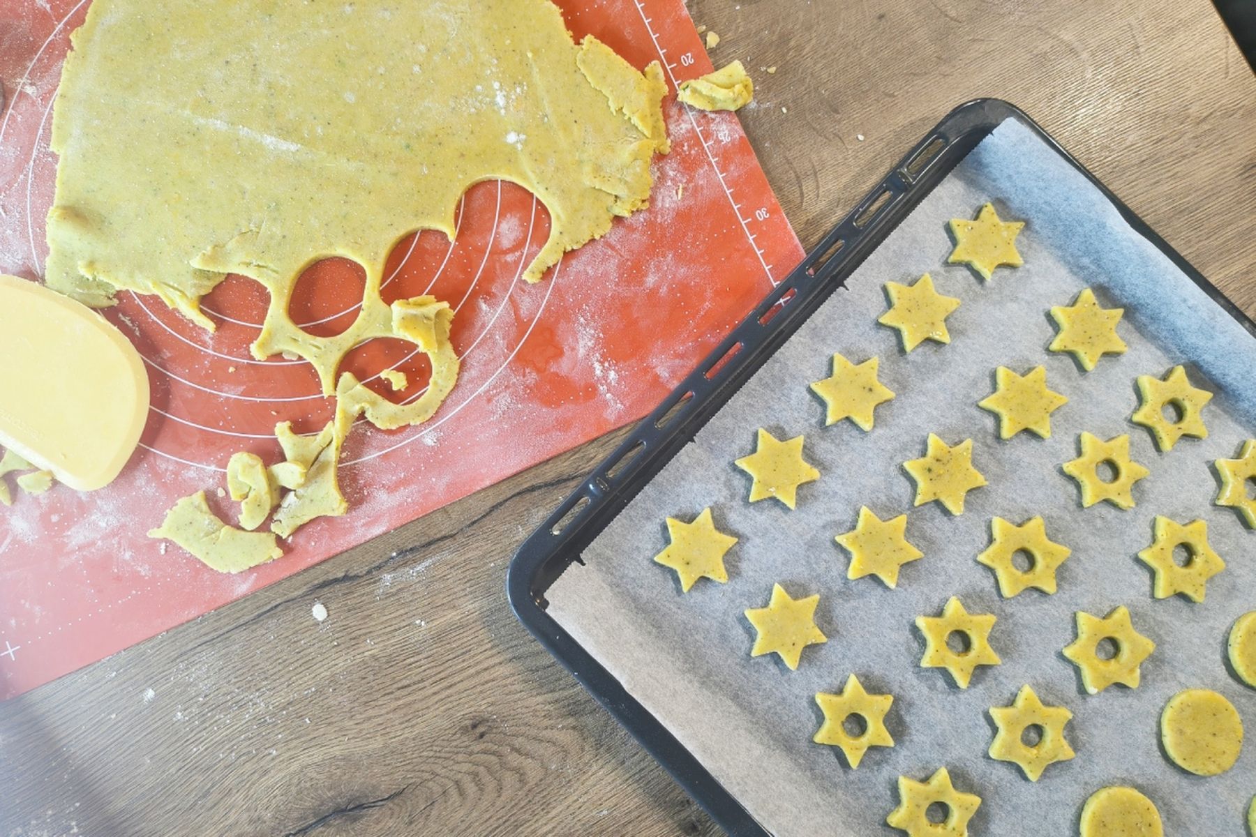 Vykrojené těsto na cukroví s hvězdičkami a kolečky vedle plechu vyloženého pečicím papírem, na kterém jsou připravené další tvary. Recept připravily Ségry v kuchyni.