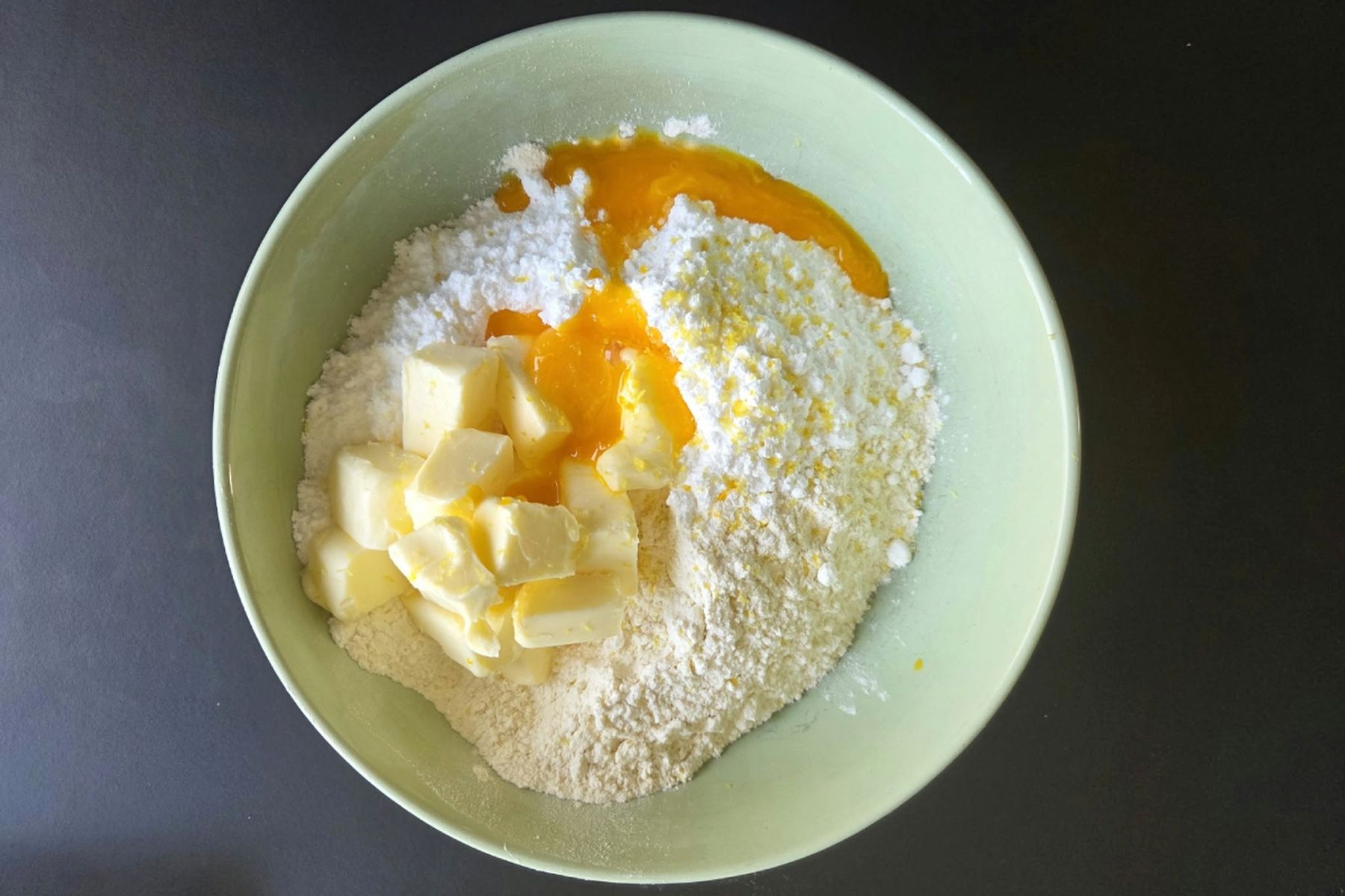 Mísa s moukou, na kostičky nakrájeným máslem, cukrem a žloutkem, připravená na přípravu těsta. Recept připravily Ségry v kuchyni.