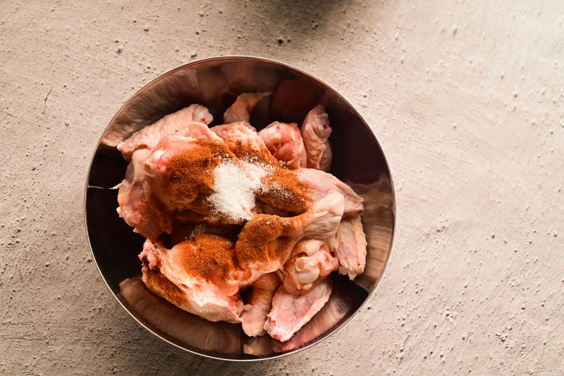 Syrová kuřecí křidélka v misce ochucená solí a kořením na strukturovaném povrchu. Recept připravil Vojta Poštulka.