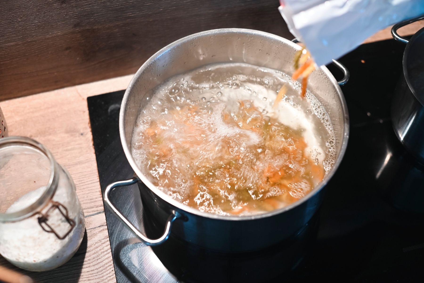 Těstoviny přidávané do hrnce s vroucí vodou na sporáku, vedle stojí sklenice se solí. Recept připravil Vojta Poštulka.