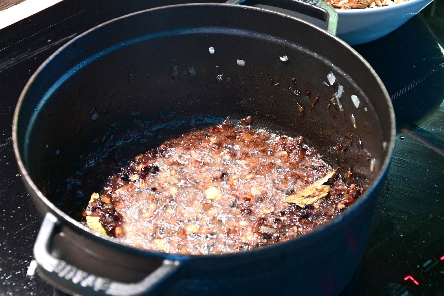 Černý hrnec na sporáku s dozlatova opečenou cibulí a bobkovým listem, která tvoří základ pokrmu. Recept připravil Vojta Poštulka.