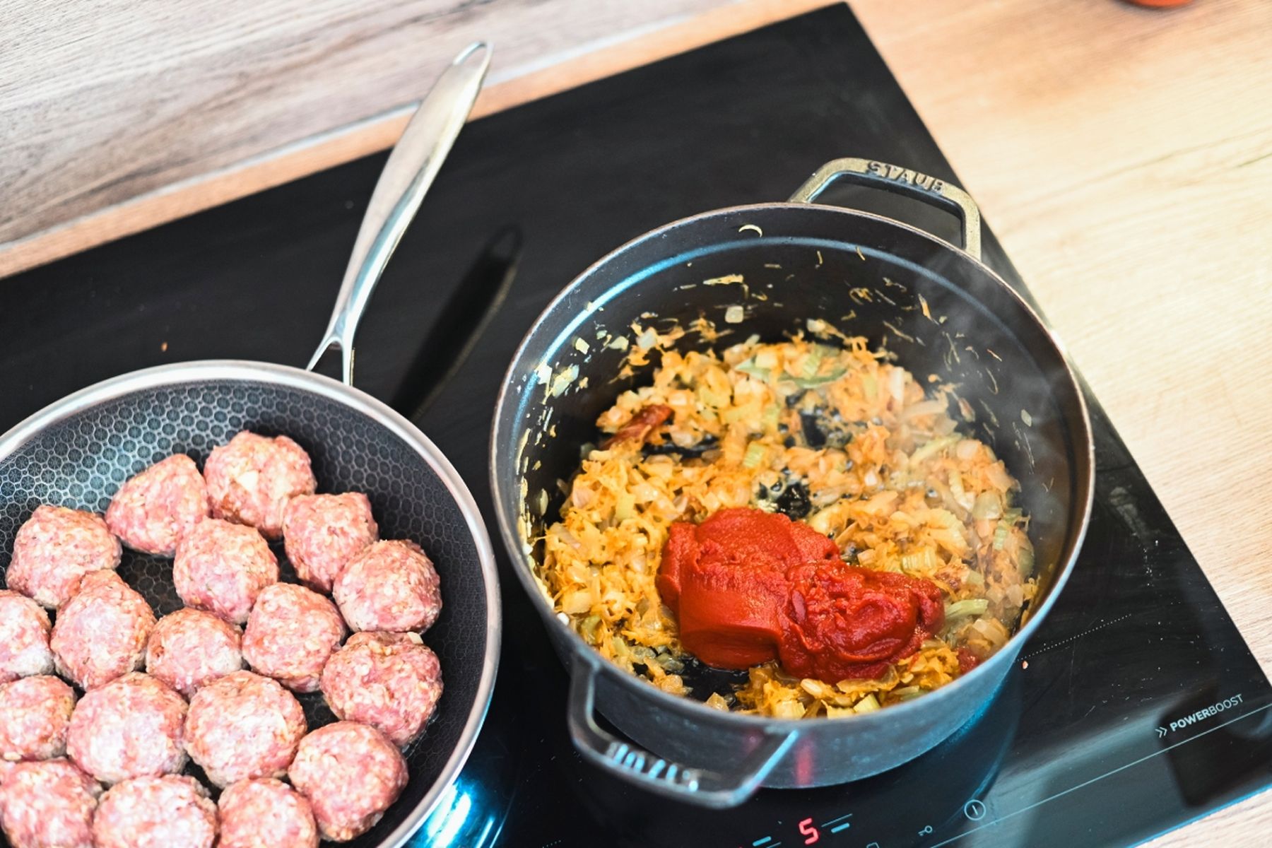 Masové kuličky na pánvi vedle hrnce s restovanou zeleninou a rajčatovým protlakem na sporáku. Recept připravil Vojta Poštulka.