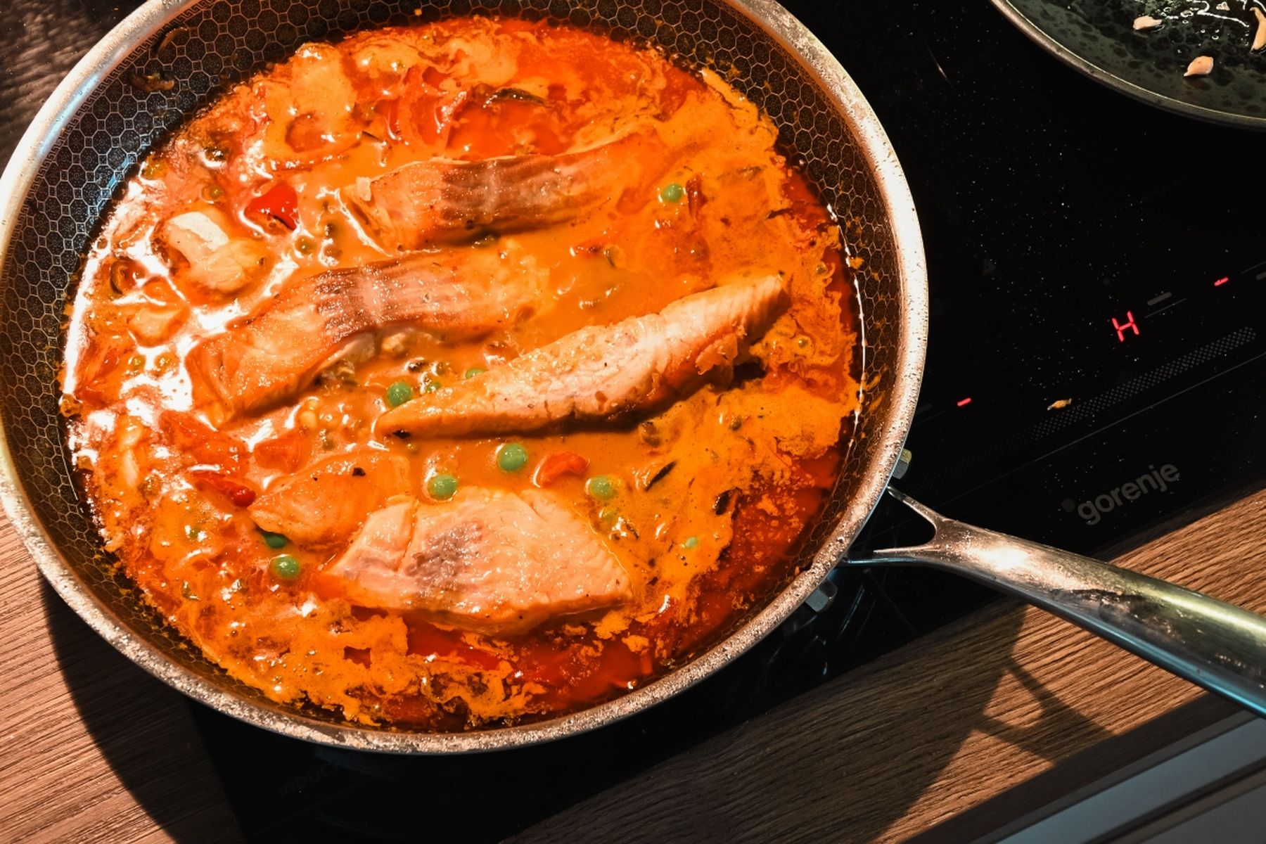 Filety z lososa připravované v červené curry omáčce s hráškem a zeleninou v pánvi na sporáku. Recept připravil Vojta Poštulka.