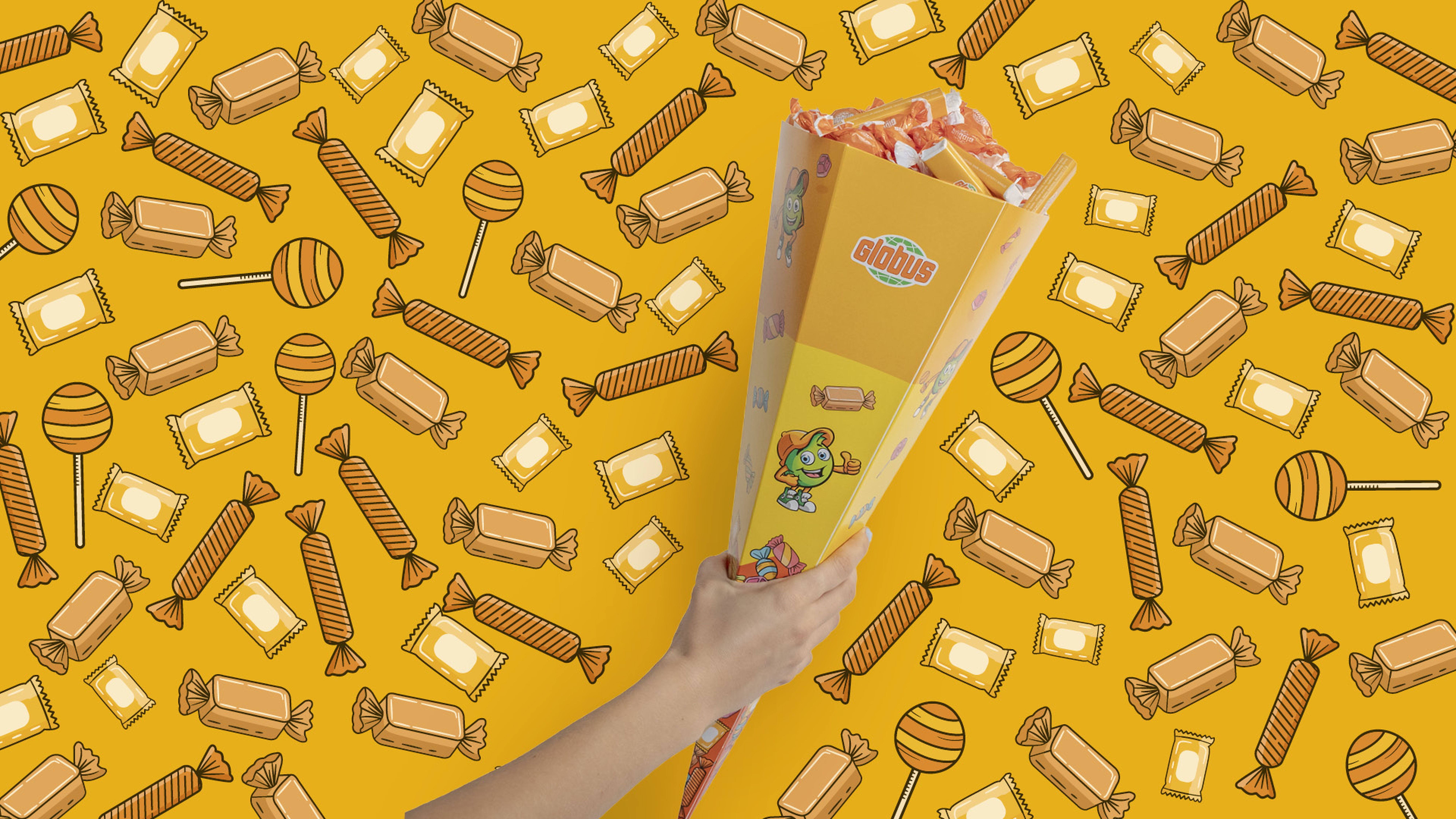 Ruka drží bonboniéru na zářivě oranžovém pozadí plném různých ilustrací bonbónů.
