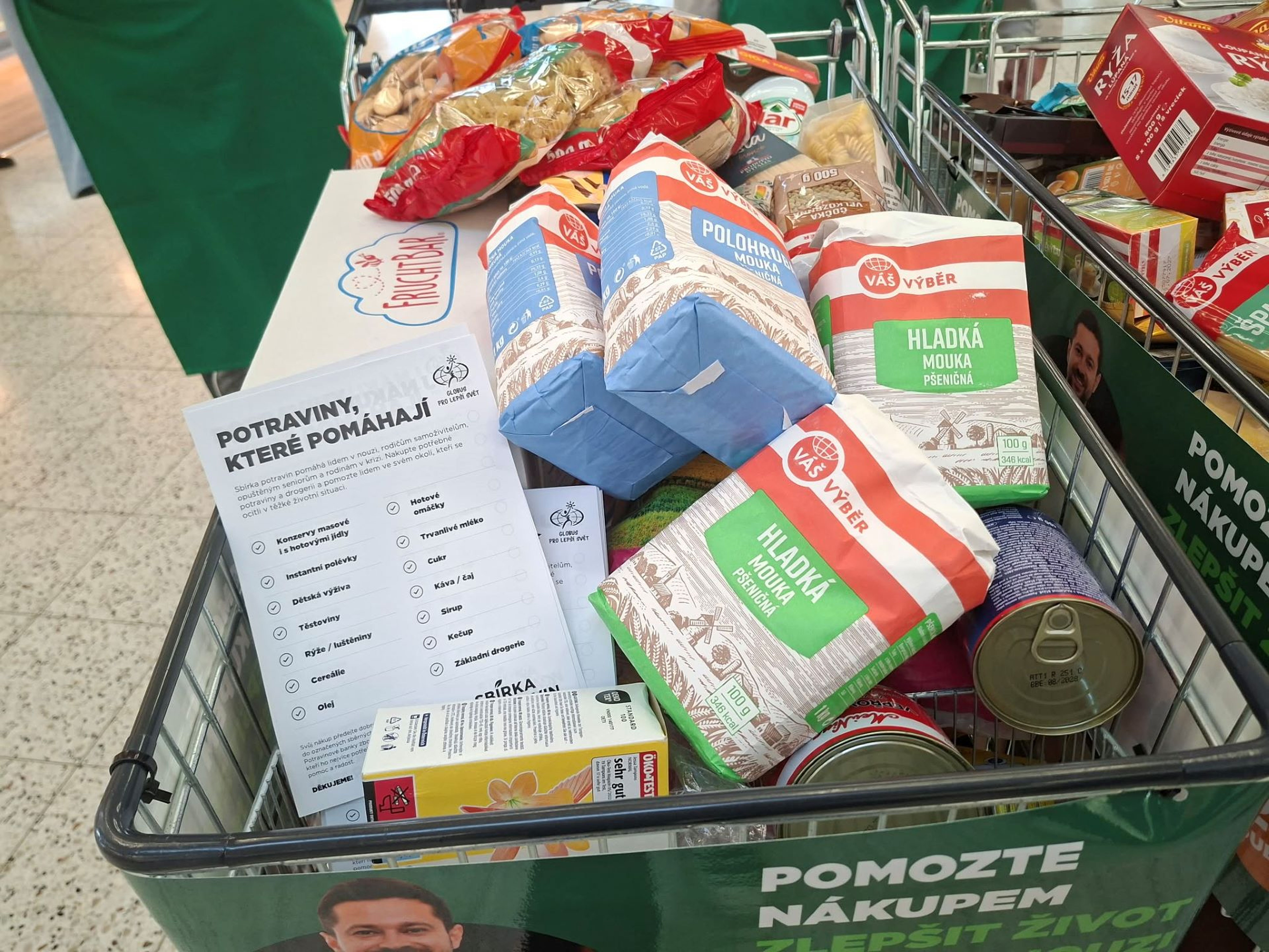 A shopping cart filled with assorted groceries and a list titled "Food that helps," promoting a food drive.