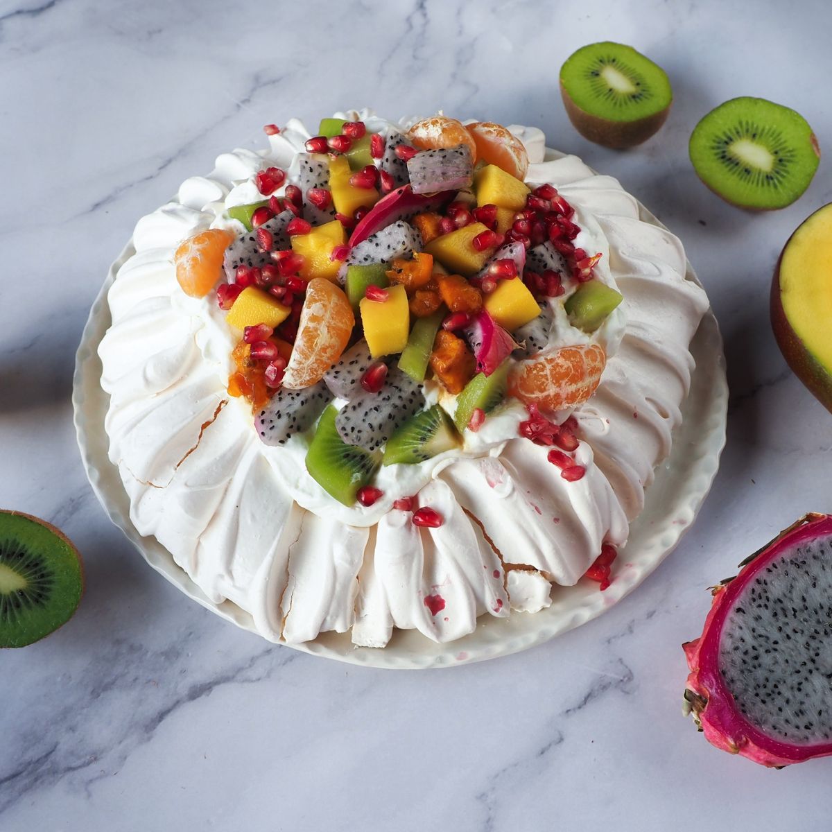 Pavlova s lehkým sněhovým korpusem a směsí ovoce – dračím ovocem, kiwi, mangem, granátovým jablkem a mandarinkami. Recept je z nabídky Globus.