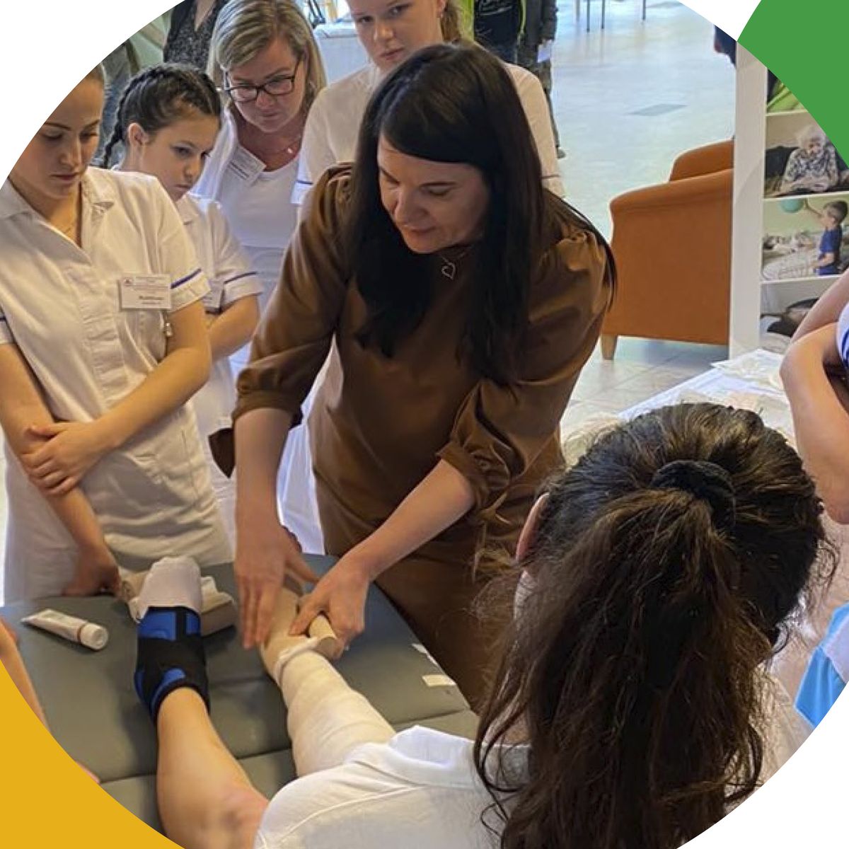 Žena předvádí, jak obvázat nohu skupině studentů medicíny v prostředí učebny.