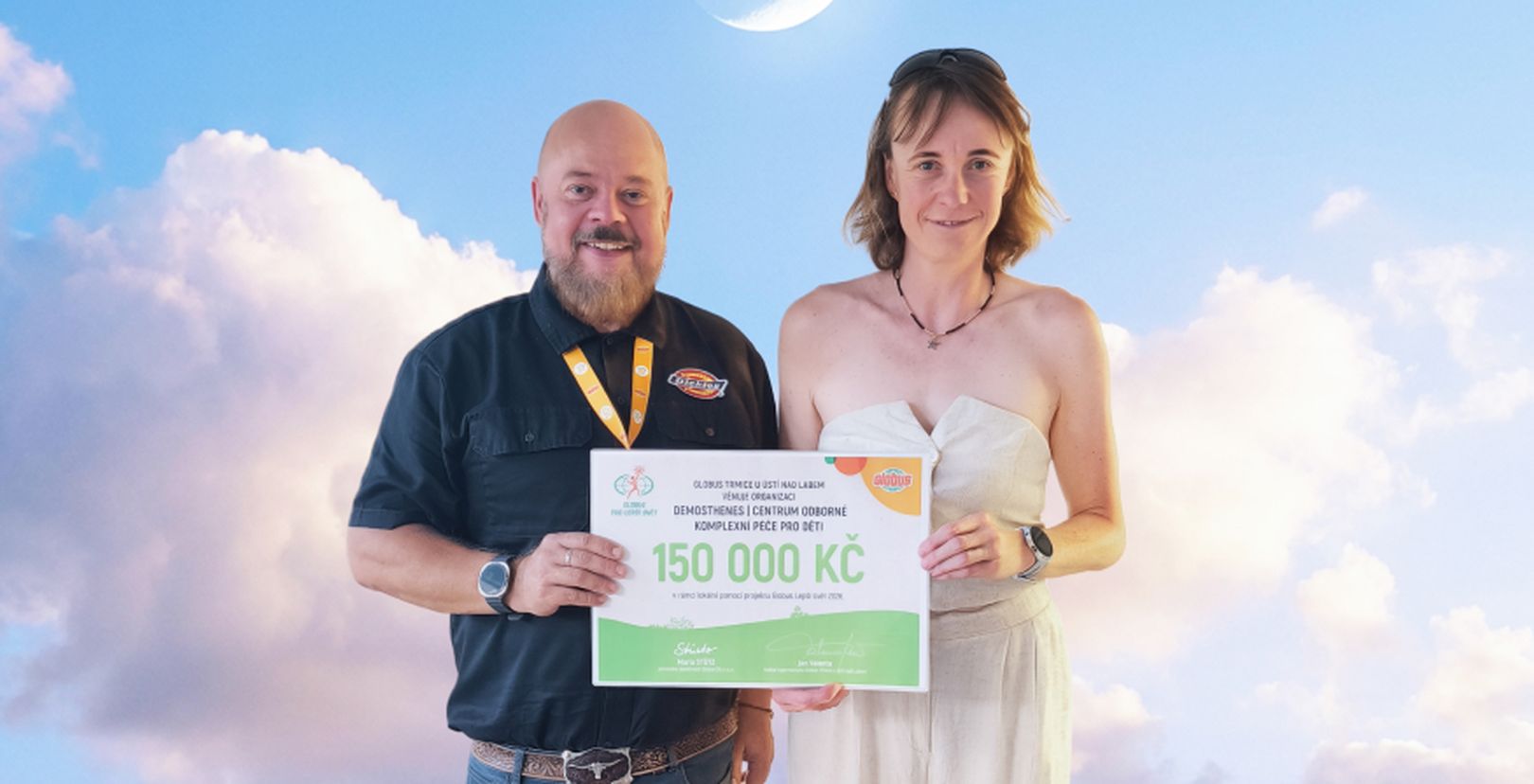 Muž a žena  s darovacím šekem na částku 150 000 před fotkou nebe