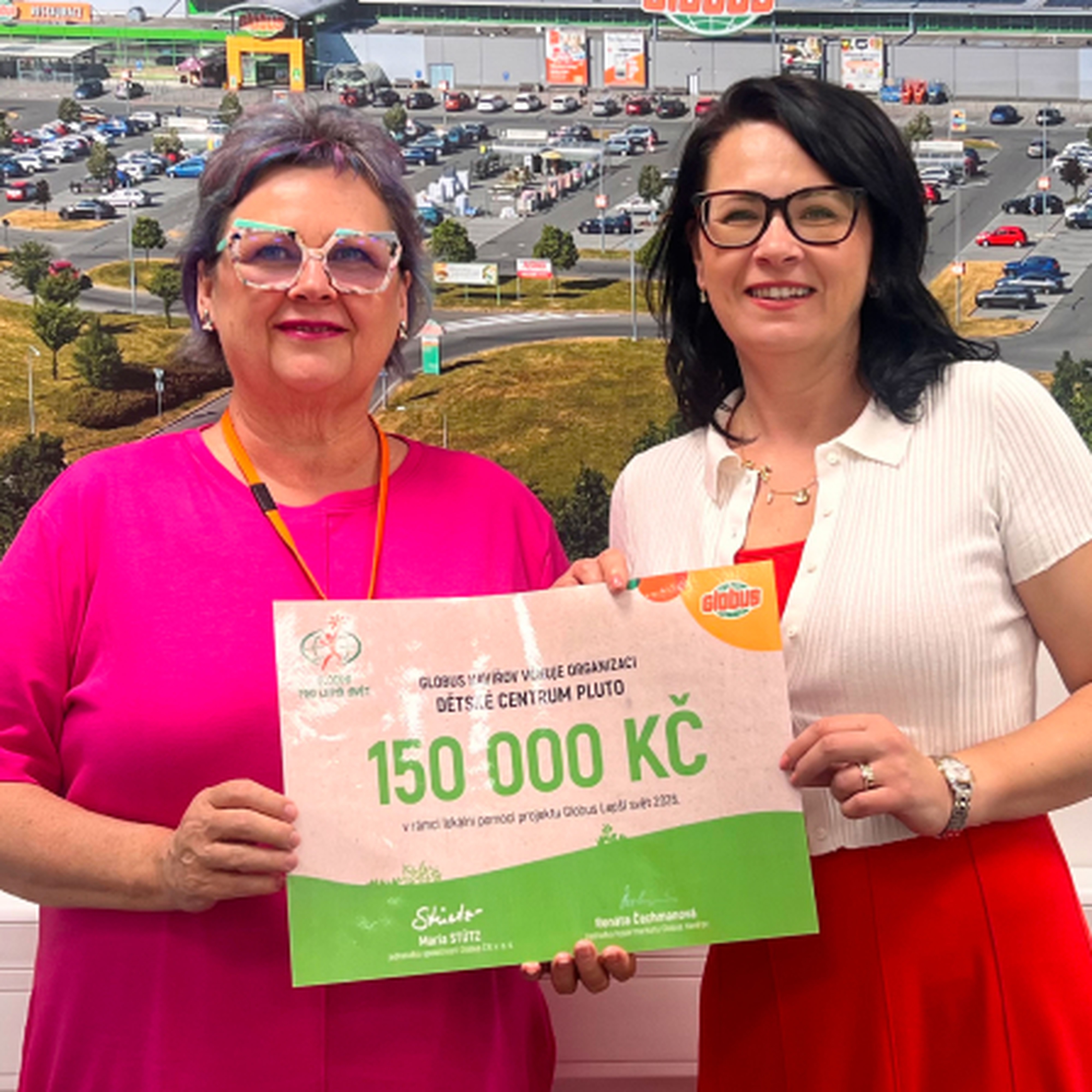 2 ženy před fotkou hypermarketu Globus s darovacím šekem na částku  150 000 Kč