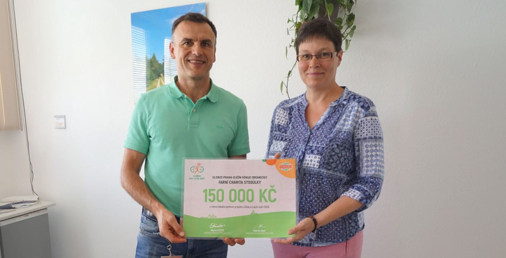 Muž a žena  s darovacím šekem na částku 150 000 Kč na bílém pozadí