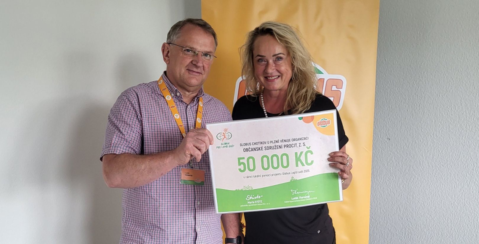Muž a žena držící šek na 50 000 Kč před logem Globus