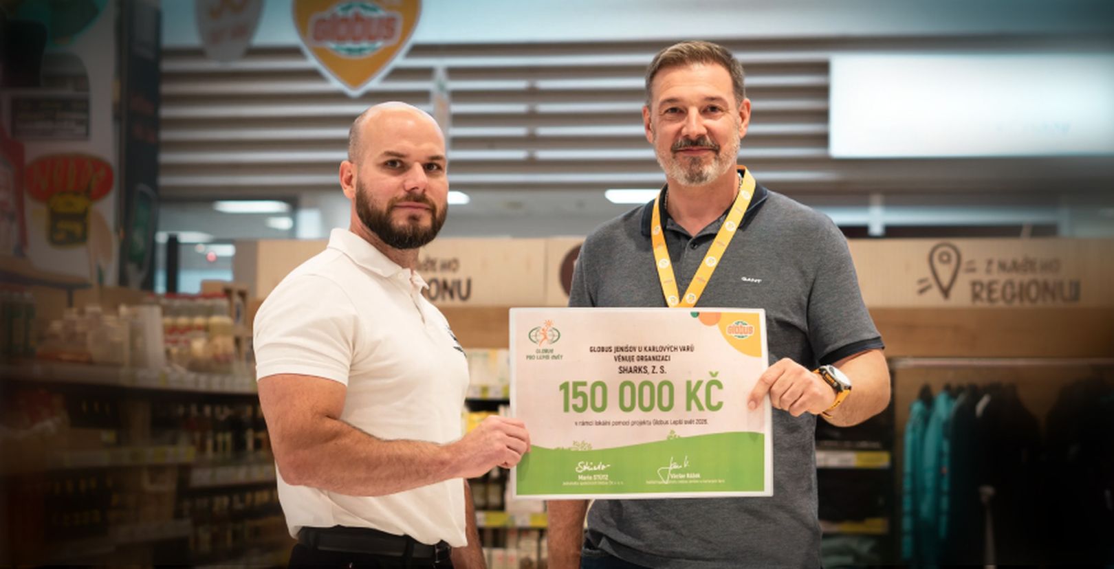 2 muži držící šek na 150 000 Kč v hypermarketu Globus