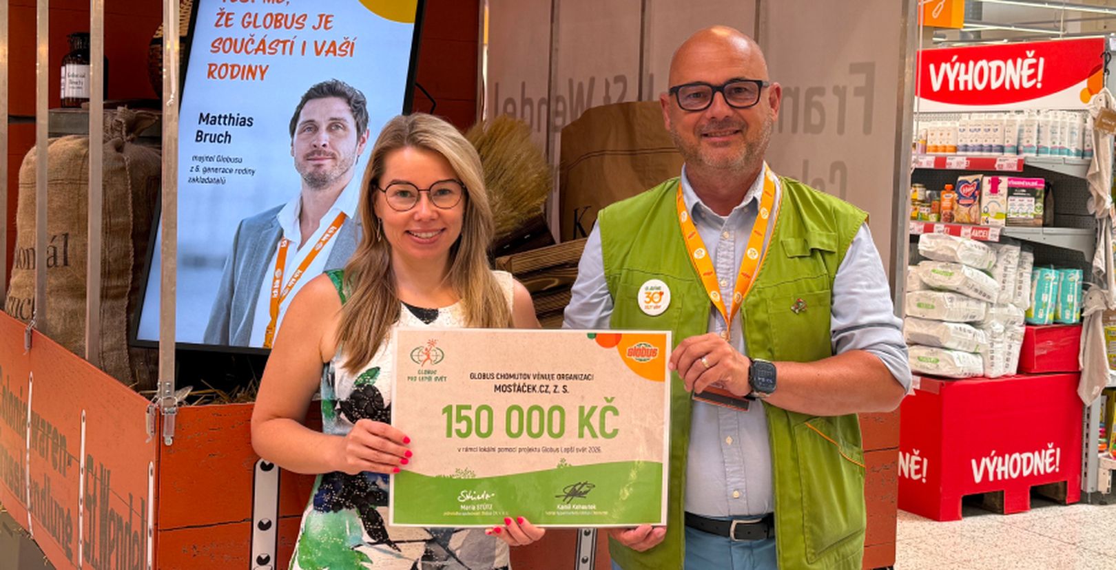 Muž a žena držící šek na 150 000 Kč v hypermarketu Globus