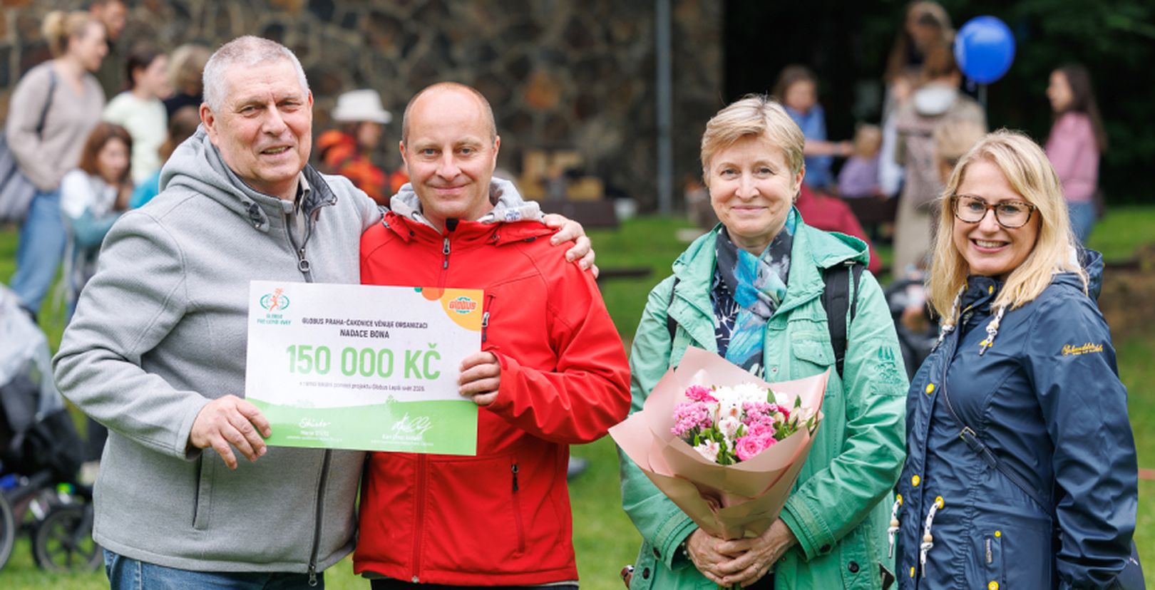 2 muži a 2 ženy v outdoorovém oblečení s darovacím šekem na částku  150 000 Kč