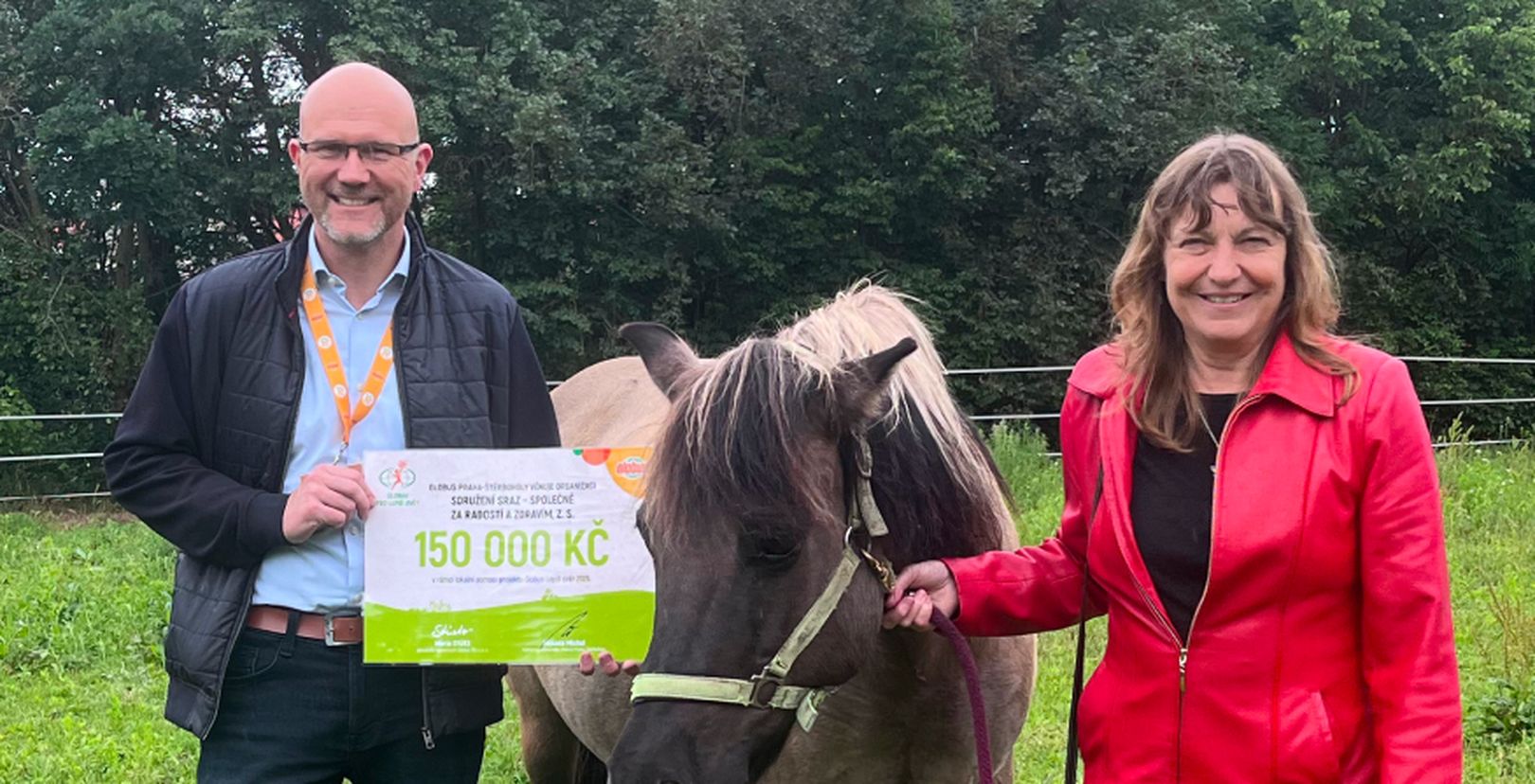 Muž a žena s koněm a s darovacím šekem na částku 150 000 Kč